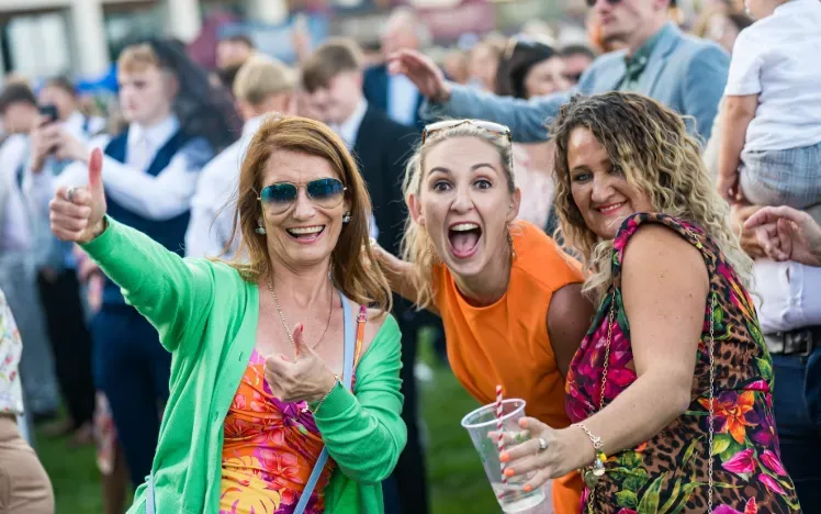 Three women in the crowd at Doncaster Races enjoy the entertainment